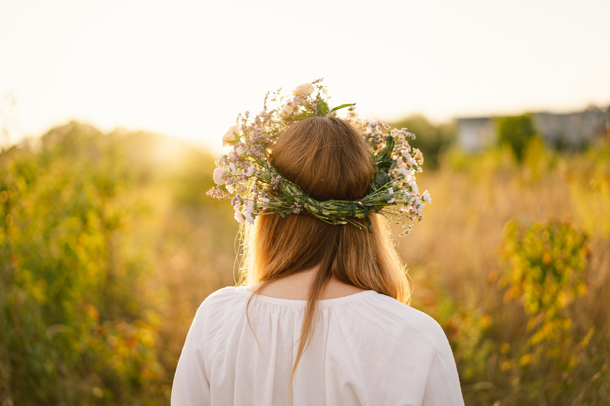 summer-lifestyle-portrait-of-beautiful-young-woman-in-a-wreath-of-wild-flowers-standing-back-in-the-flower-field-hands-to-the-side